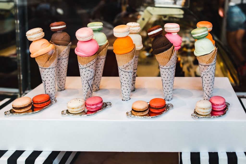 a photo of the shop front window of an ice cream shop, showing multiple cones with different coloured ice cream and toppings.