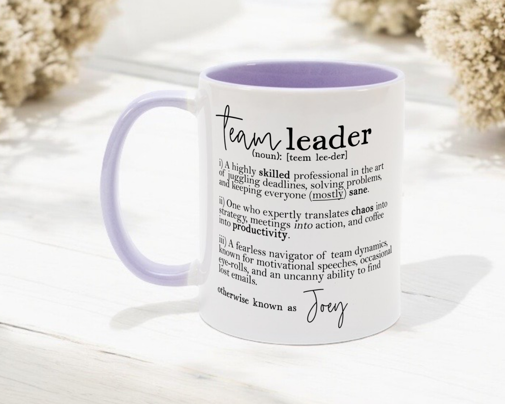 a lilac two-tone classic ceramic mug pictured on a white background, the mug reads 'team leader' followed by a dictionary-style definition that is followed by a personalised name.